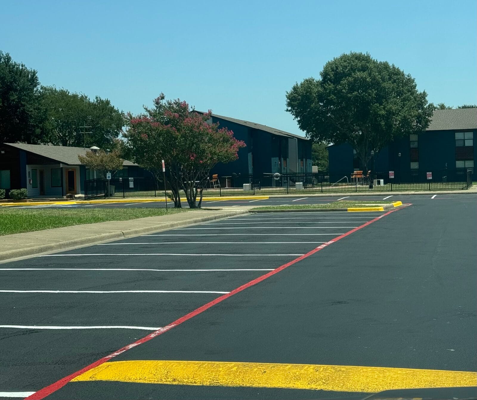 Newly seal coated parking lot with crisp white stalls, red fire lane and yellow curb, Cedar Hill TX