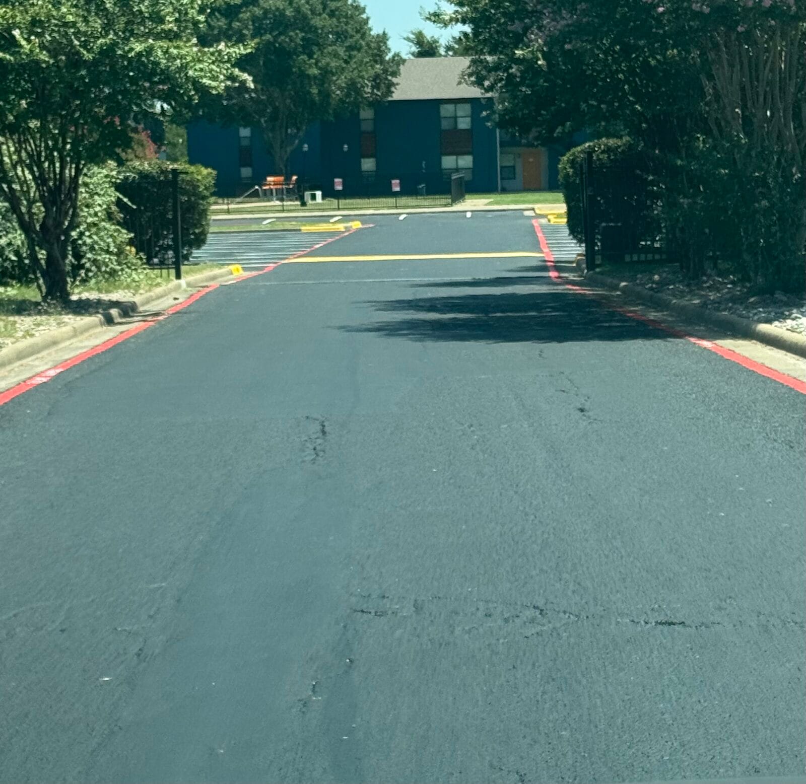 Freshly seal coated asphalt drive lane with new red fire-lane striping, Cedar Hill TX