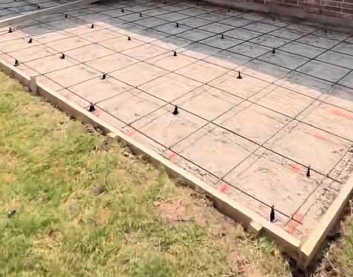 Rebar grid on chairs inside wood forms, doweled into the existing slab, ready for the concrete add-on extension pour in Dallas TX