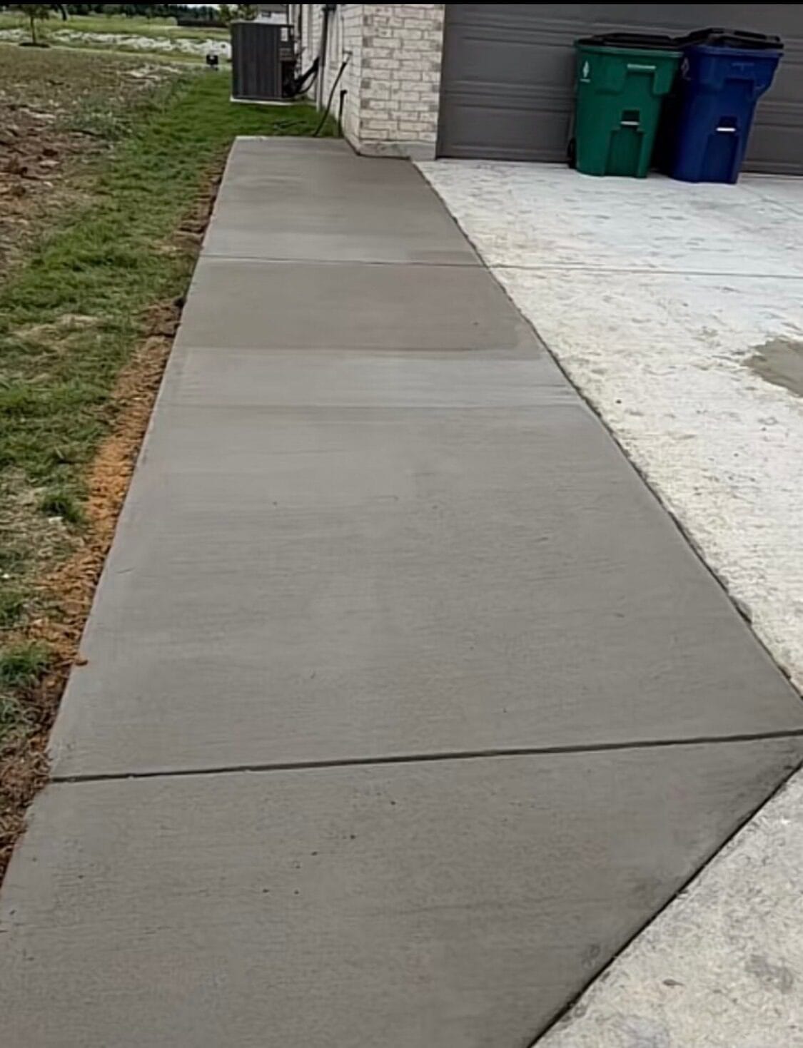 Widened concrete driveway extension running alongside the garage to the back of a Waxahachie TX home