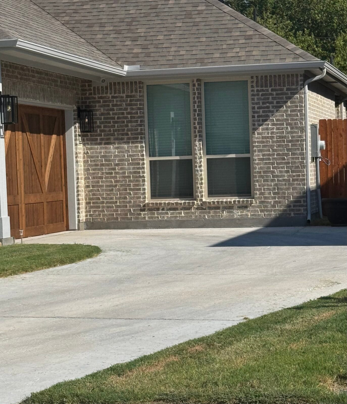 Finished concrete driveway installation with a wide turning apron at the garage of a Dallas TX brick home