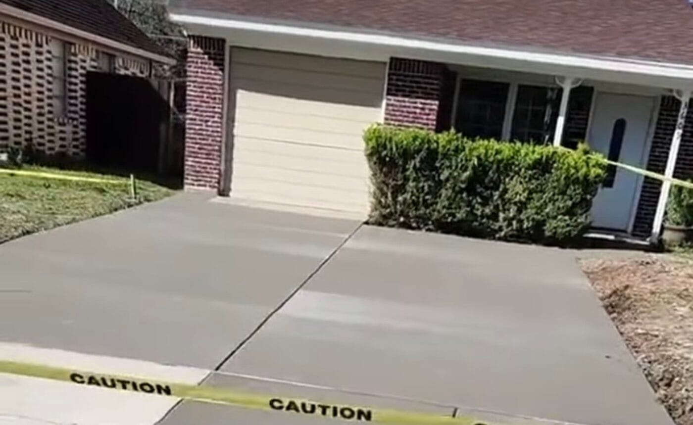 Newly poured concrete driveway with a smooth finish leading to the garage on a North Texas brick home