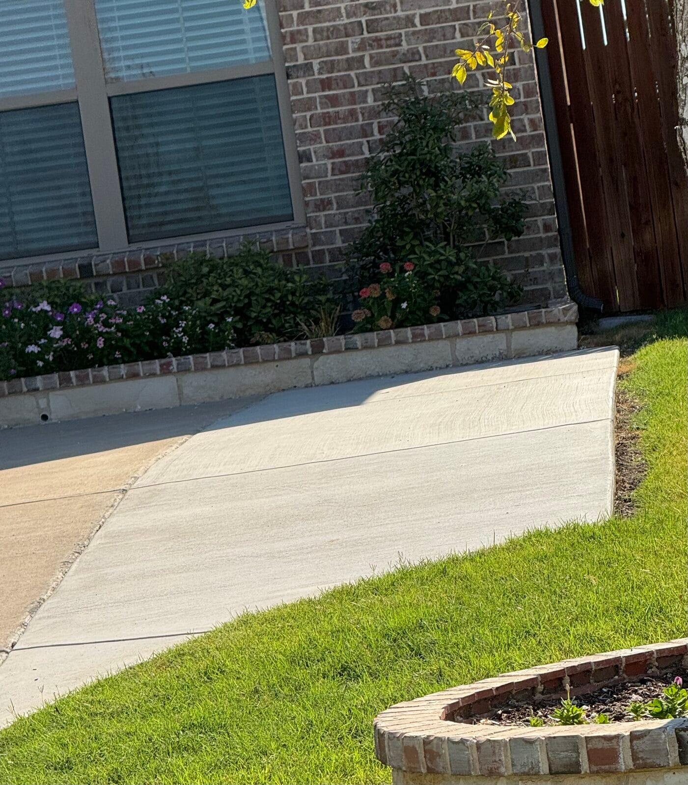 Finished concrete driveway extension with clean control joints beside a brick home in Glenn Heights TX