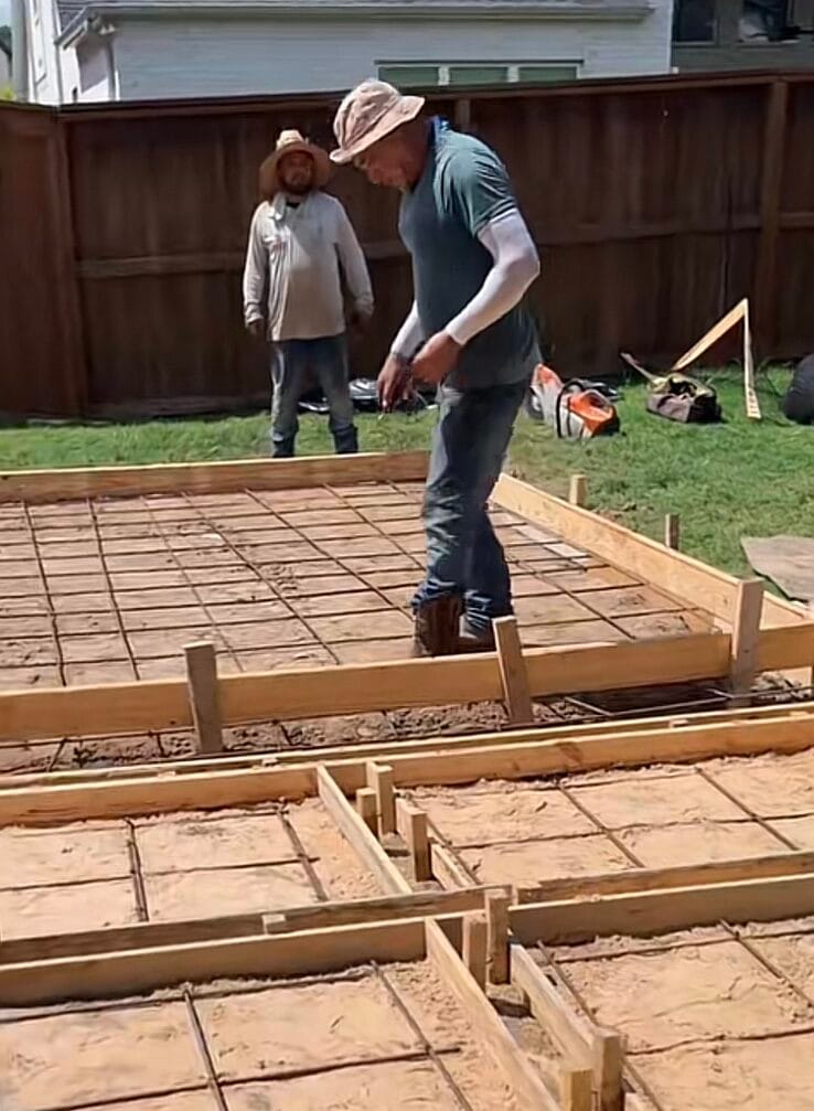 Concrete crew checking form layout and rebar spacing before pouring the patio pads in a DeSoto TX backyard