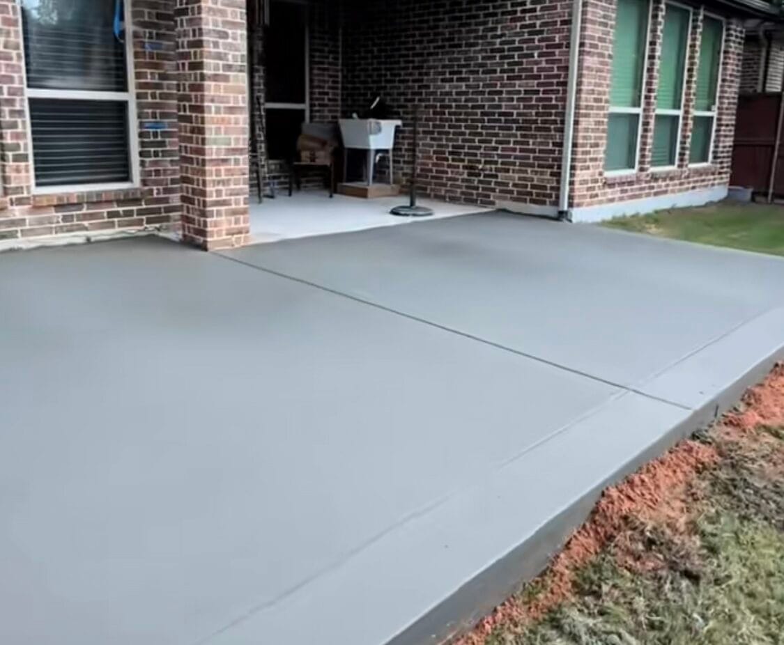 Freshly finished concrete patio slab spanning the back of a brick home in Waxahachie TX