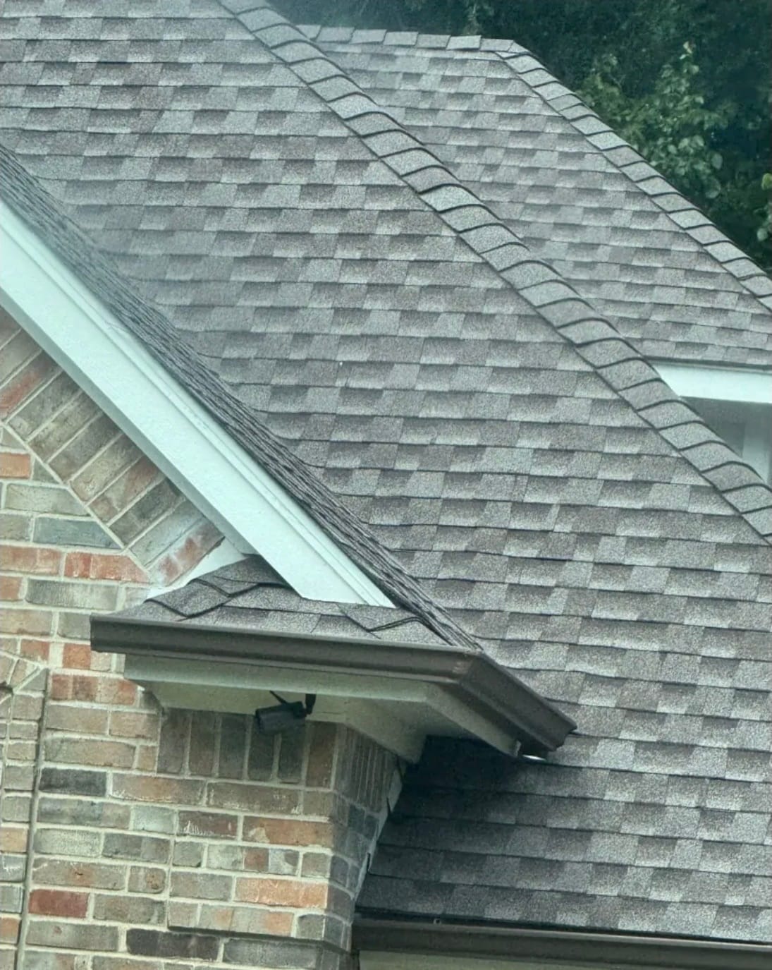 Freshly installed architectural shingles with new ridge cap and clean fascia line on a DeSoto TX brick home